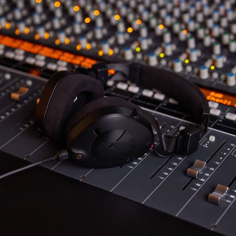 Rode NTH-100 headphones on professional mixing console with faders and studio equipment